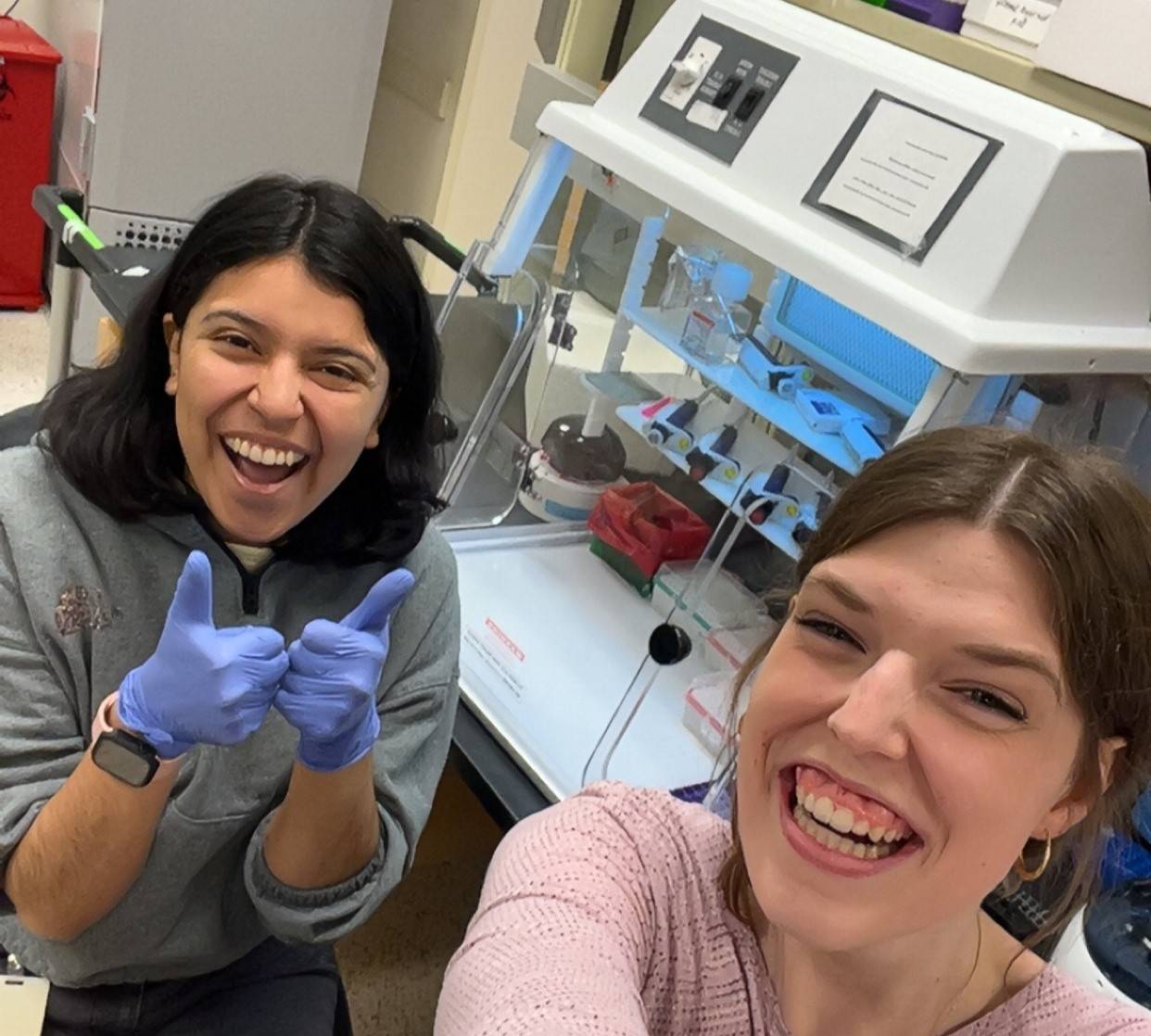 two girls smiling with biology equipment in the background